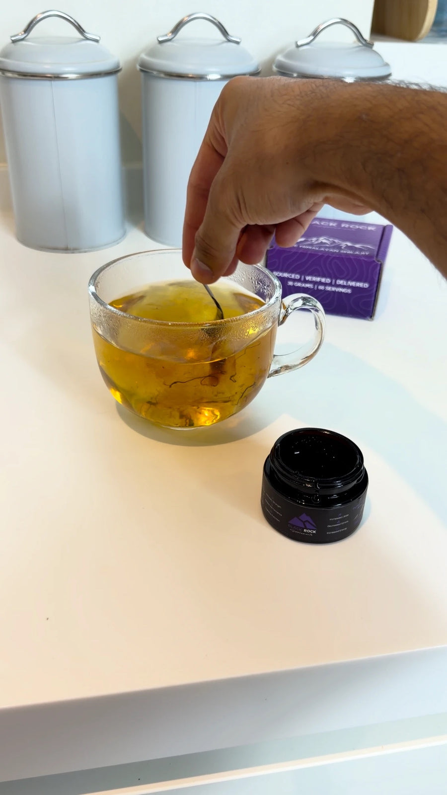 Stirring Shilajit resin into a glass mug of warm tea
