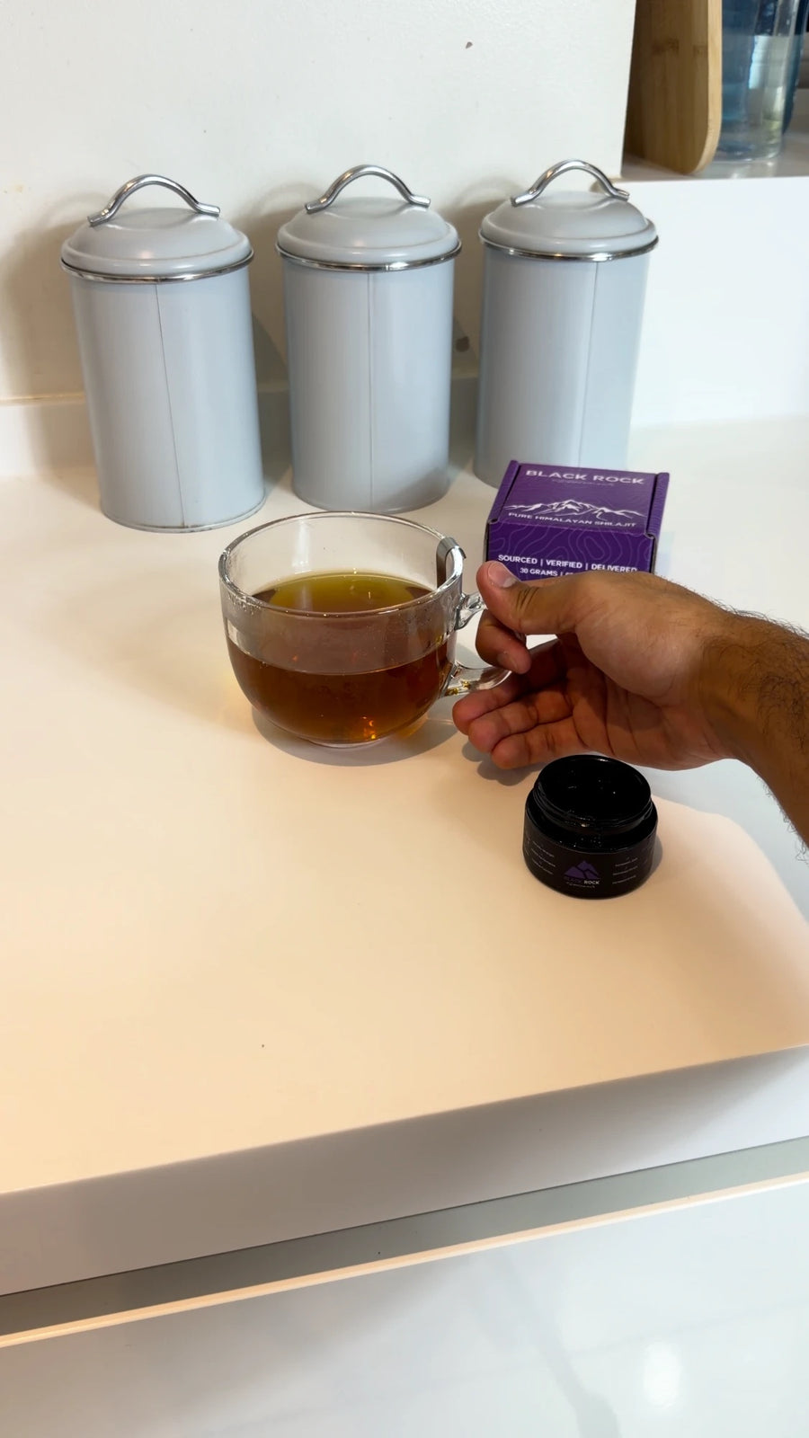 A finished mug of tea with Shilajit dissolved, next to the jar