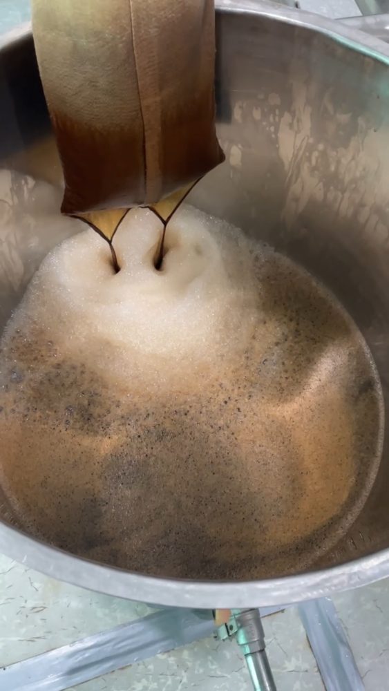 Raw Shilajit straining through a filter bag into a stainless vessel