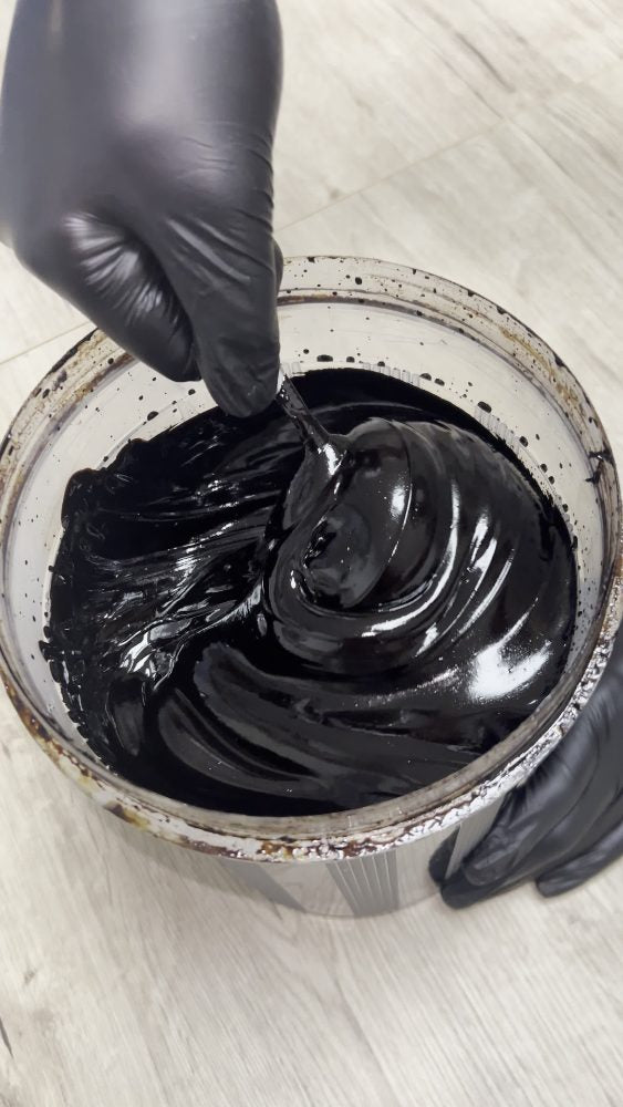Finished near-black glossy Shilajit resin worked with a spatula